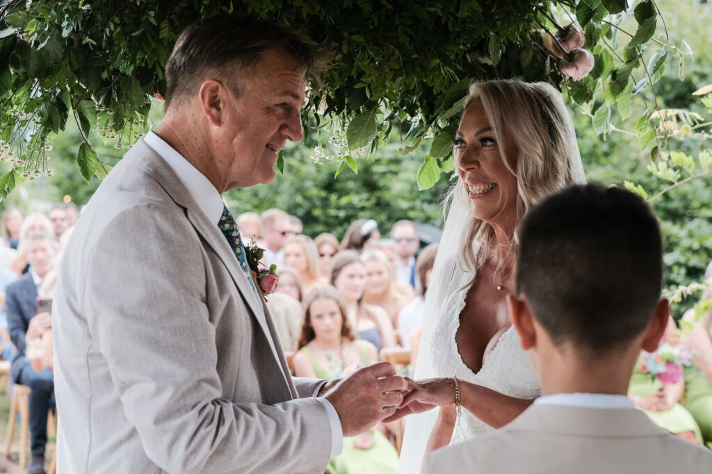 Groom placing wedding ring on bride, Willow Grange farm