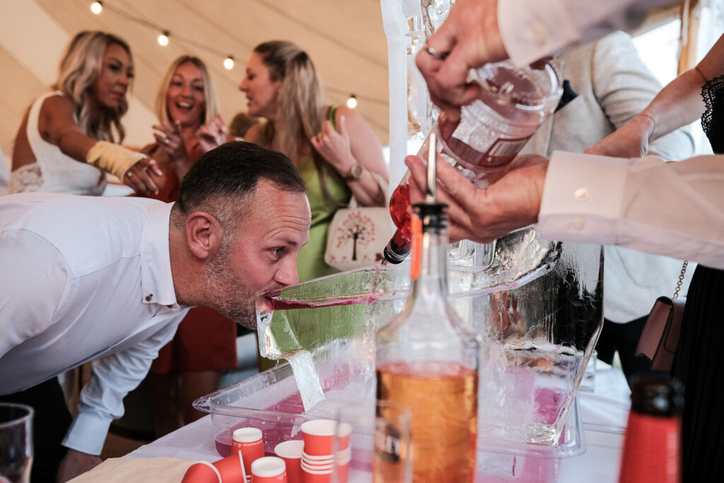 Wedding guest drinking vodka from the ice sculpture, Willow Grange farm 